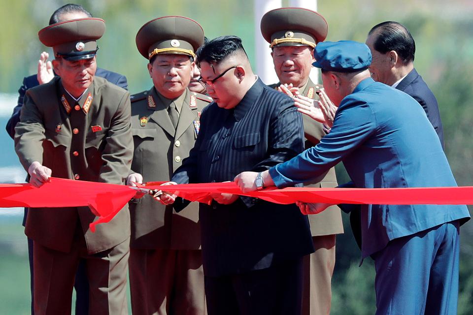  The new images also see despot ruler Kim Jong-un, fourth right, standing with officials as he cuts the ribbon at new high-rise opening in Ryomyong