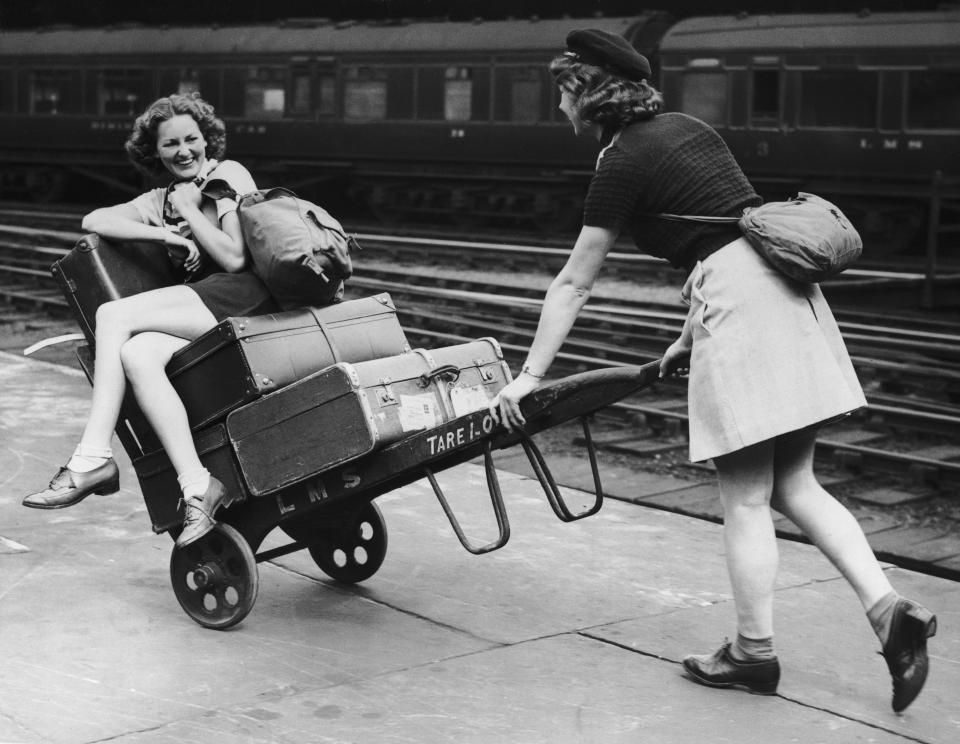  Two holidaymakers amuse themselves with a porter's trolley whilst waiting for their train at Euston Station in 1939