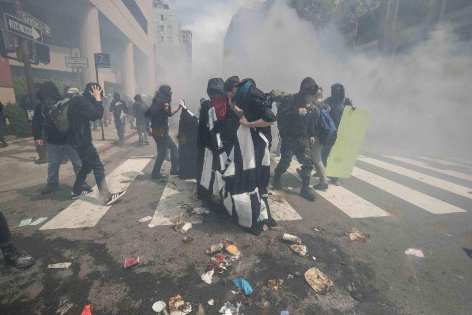 Anti-Trump protesters gather together amid smoke from a smoke bomb at Milvia St. and Center St. in Berkeley