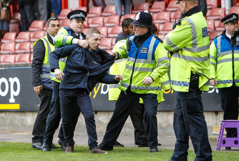  A fan is collared after getting onto the pitch