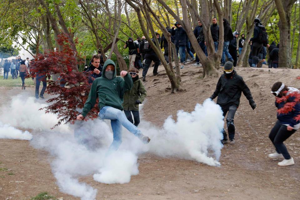  A demonstrator kicks away a tear gas canister after it was fired by police