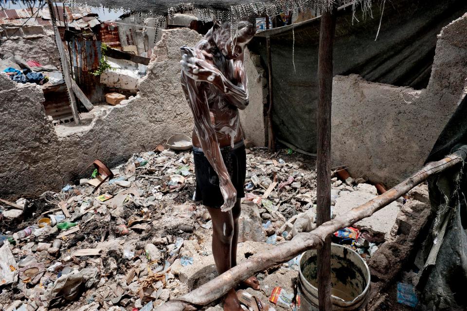  A boy is having a shower inside his house destroyed by the huge earthquake in 2010