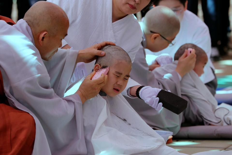 Two children react as monks shave their heads 