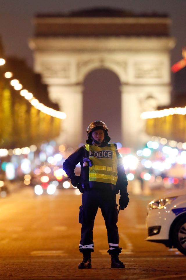  An armed policeman stands guard with the Arc de Triomphe in the background