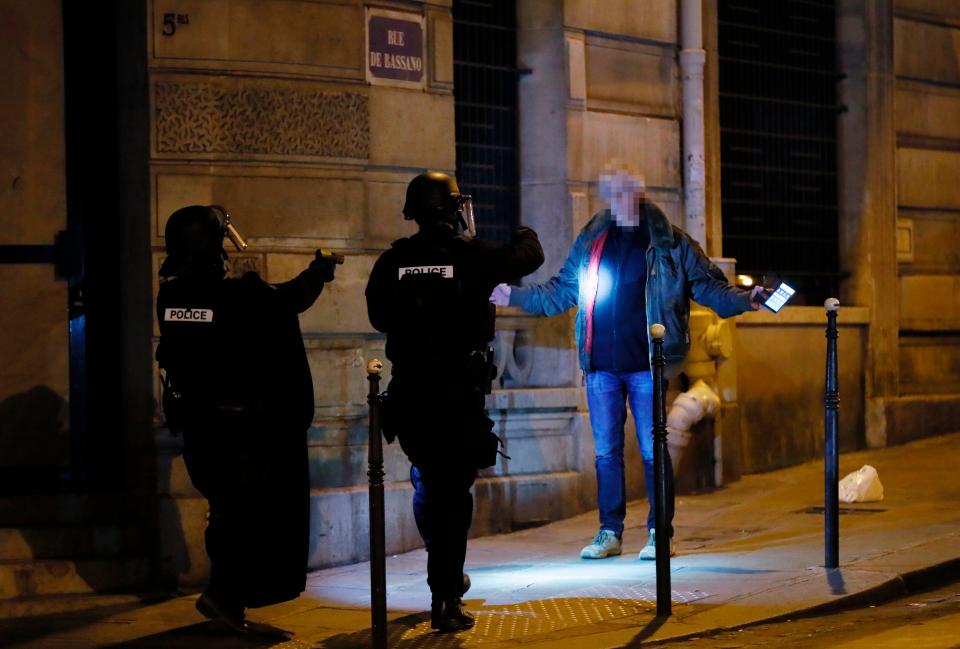  A man raises his arms in front of police officers close to the scene in Paris