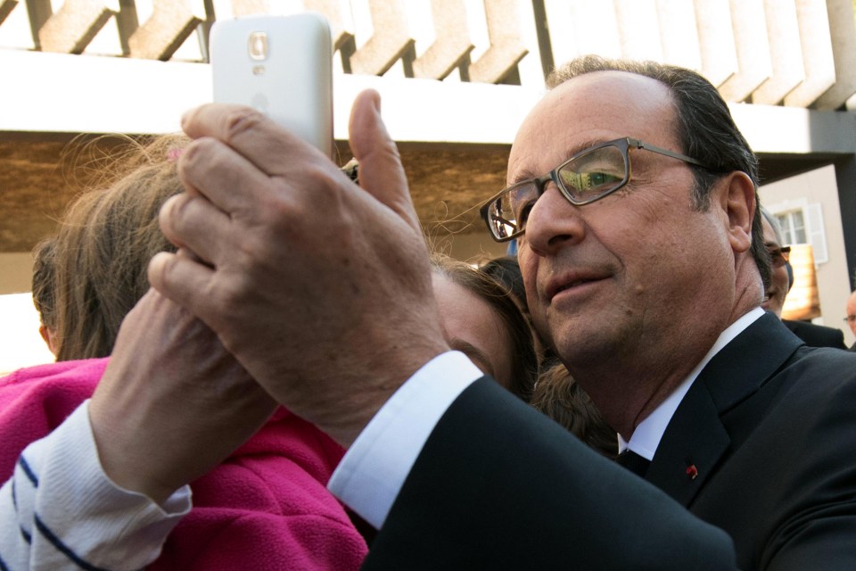 Current French President Francois Hollande takes a selfie with a supporter after voting in Tulle, central France