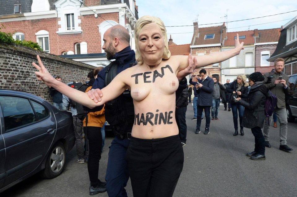 Police escort a topless Femen activist wearing a Le Pen mask away from the polling booth