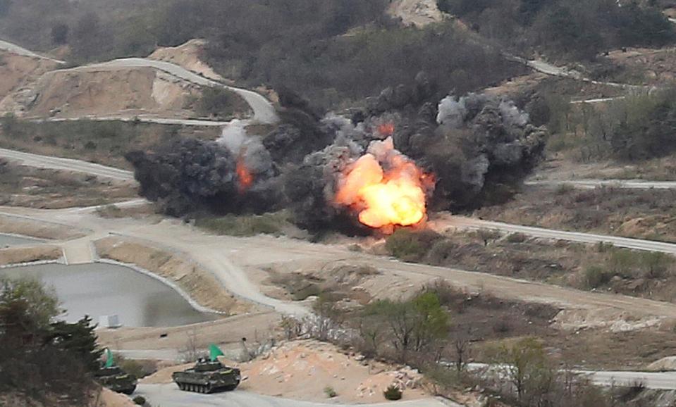  Flames rise from a powerful explosion as the South Korean army's armoured vehicles wait for further instructions