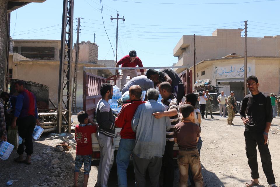  Civilians in Mosul receive aid supplies from the back of a truck