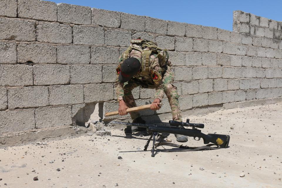  A sniper makes a hole in a wall on a rooftop in order to fire from behind cover