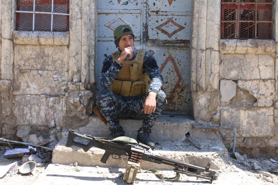  An Iraqi Federal Police officer smokes a cigarette while resting in Mosul