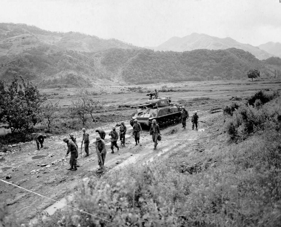  Soldiers using mine detectors to sweep the road clear of hidden Communist-planted land mines for an advancing M-4 tank, 10 June 1951