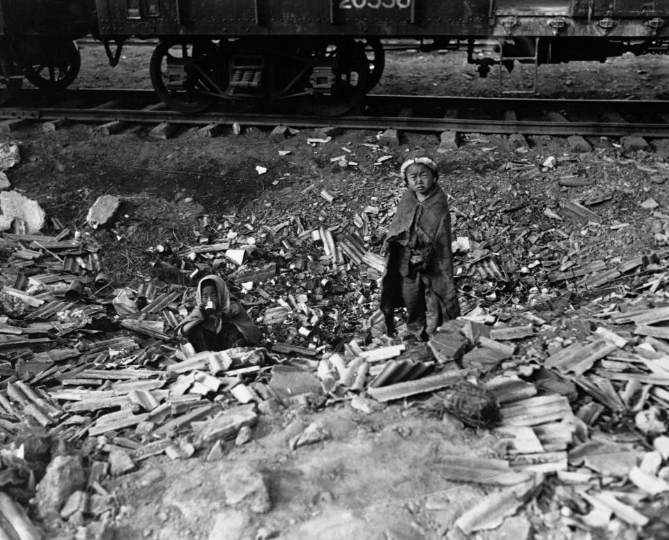  Homeless, this brother and sister search empty cans for morsels of food and try to keep warm beside a small fire in a railroad yard