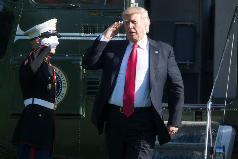 An ever confident looking Trump salutes a US Marine yesterday while walking off Marine One after arriving on the South Lawn of the White House