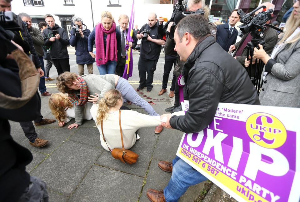  UKIP supporter holding a party banner is seen desperately trying to separate the women as they fall to the floor