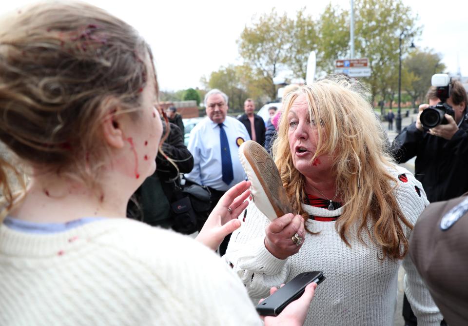  After the bloodied women rose to their feet, they continued arguing while one waved her shoe