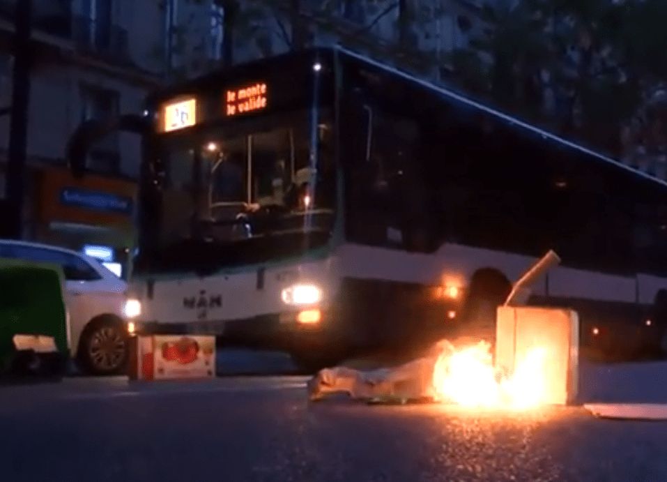  A small fire is left in the middle of the road near a bus as rioters move through Paris