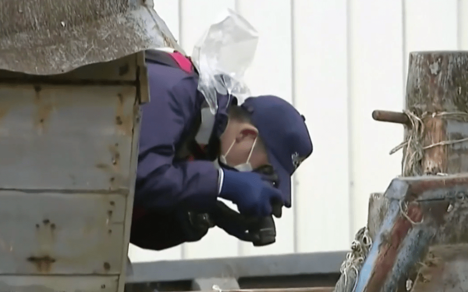  An investigator examines one creaking 'ghost ship' after it washed up in Japan