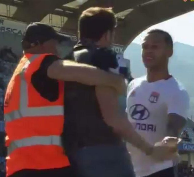  Lyon staff member try to stop a supporter who invaded the pitch to clash with Memphis Depay