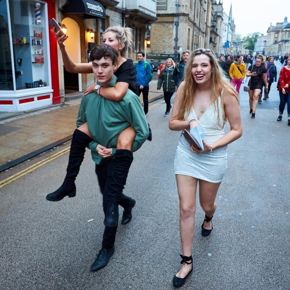  A man gives his friend a piggy back as they walk to this morning's May Day celebrations in Oxford