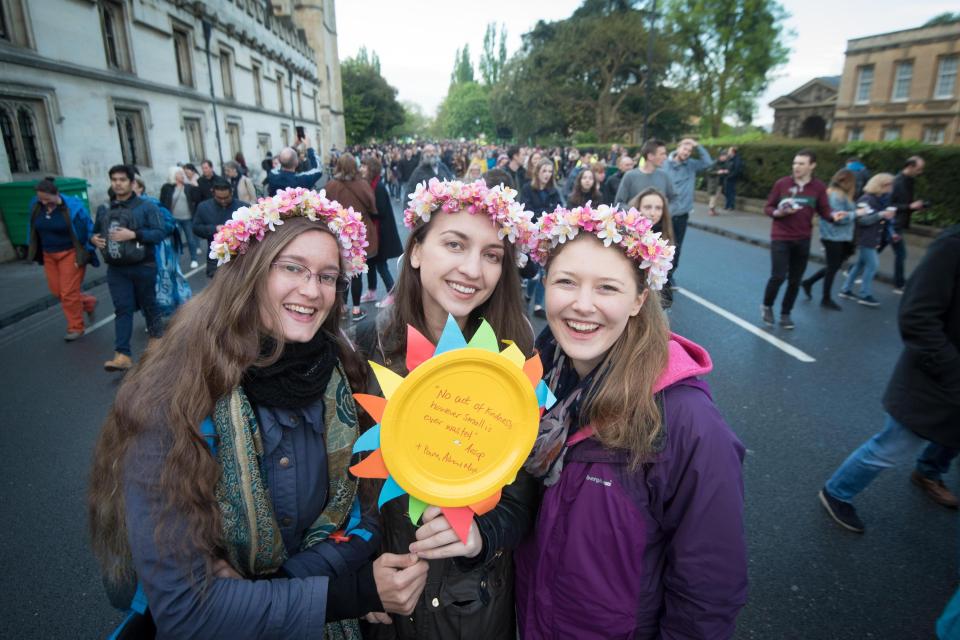  Three girls wrap up warm and carry a home-made sign welcoming the start of summer in Oxford