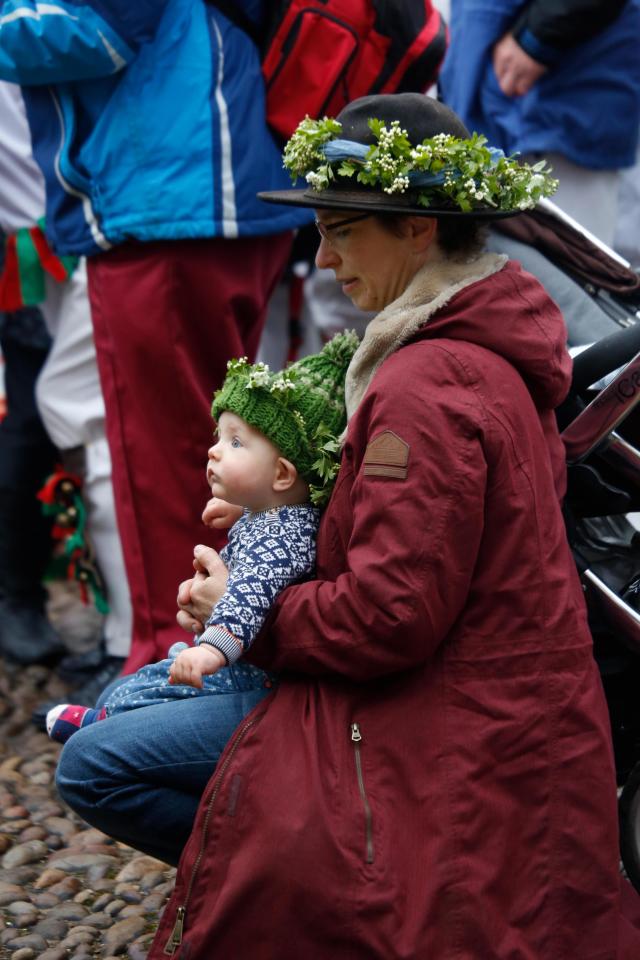  A woman and baby wearing hawthorn sprigs on their hats join in the festivities in Oxford