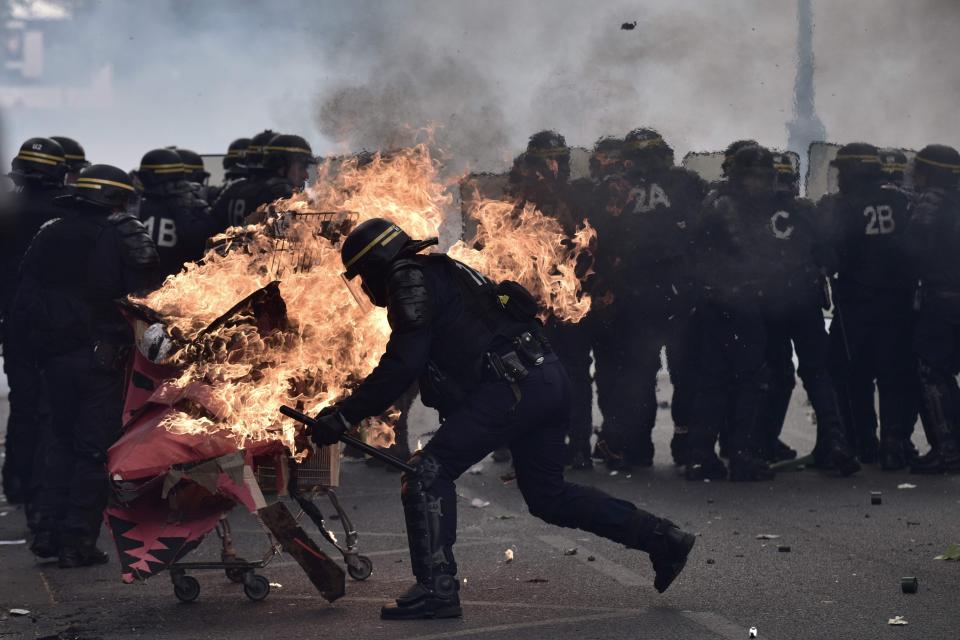  French riot cops try to push away a burning trolley launched towards them during the annual May Day workers' rally in Paris