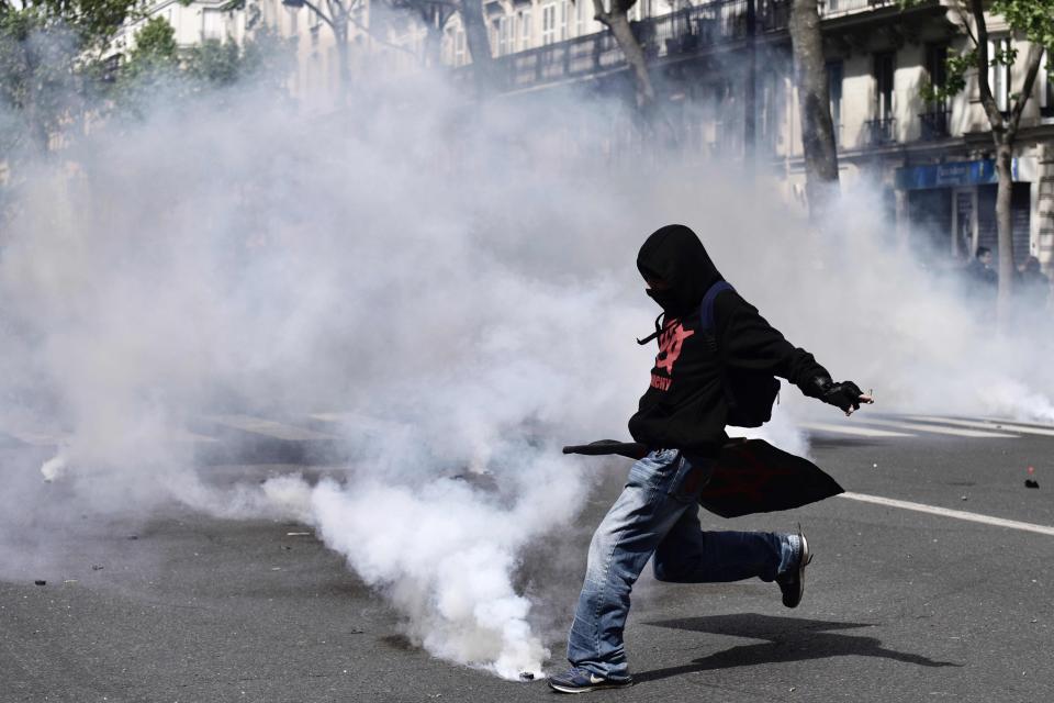  A demonstrator kicks a tear gas canister back towards police lines during clashes in Paris today