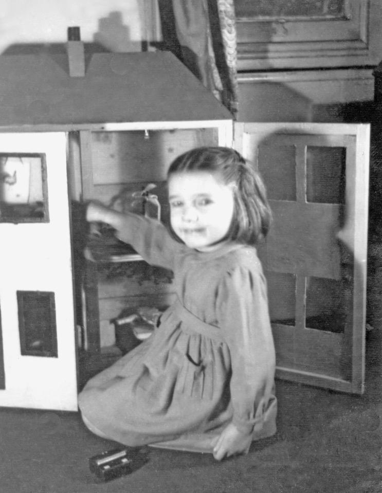  A little girl plays with her dolls house in the 1950s. The toy was made out of an old orange box as wood and paper was in short supply