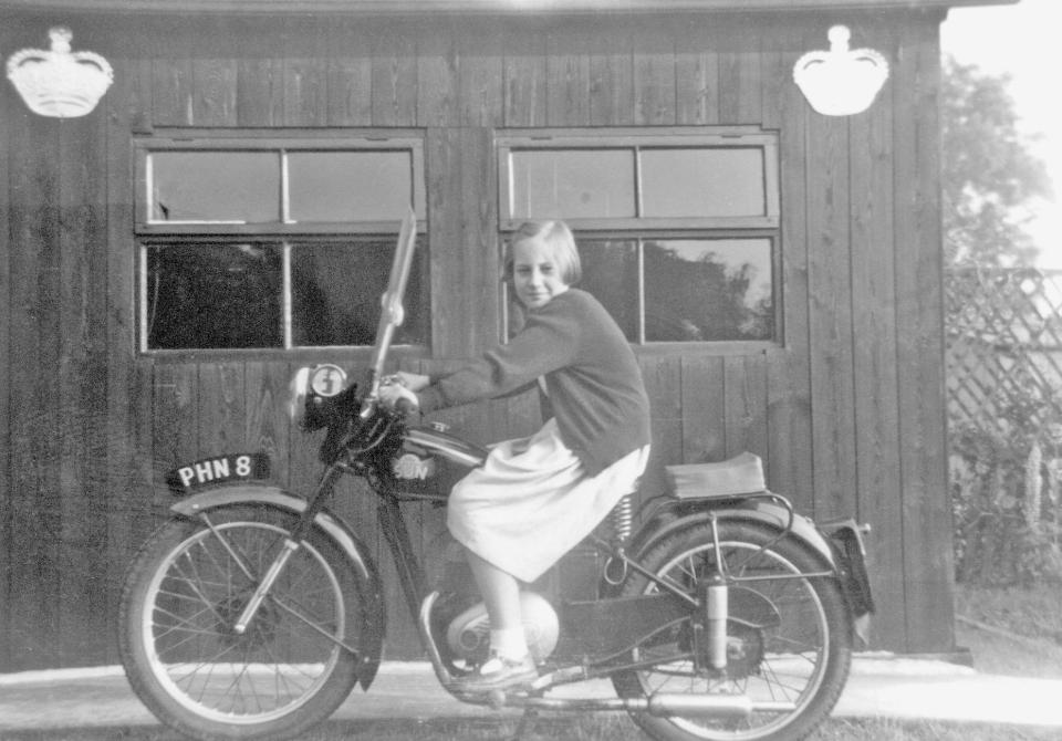  Christine Watson sitting astride the family motorbike in 1953 outside a garage decked in bunting for the Coronation