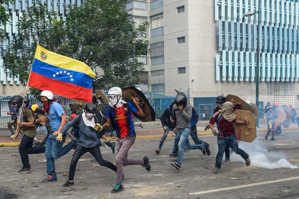  Demonstrators wave the Venezuelan flag as they retreat from charging riot police