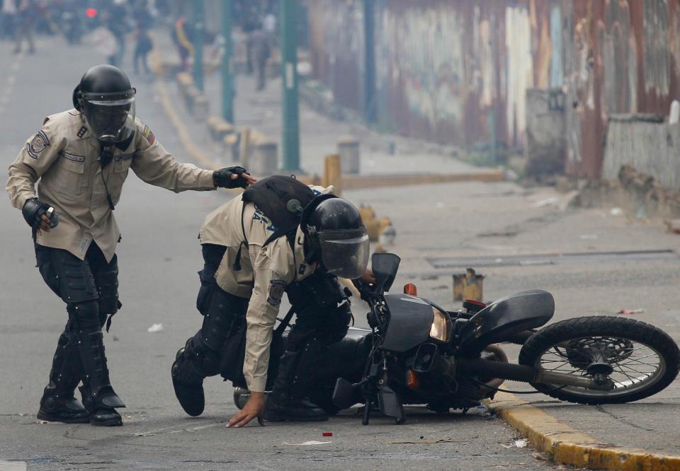  Members of the Bolivarian National Guard desperately scramble after falling off a motorbike