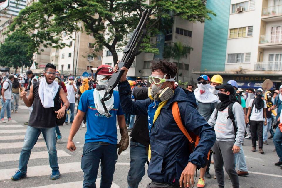  An armed protester leads dozens of masked men towards police