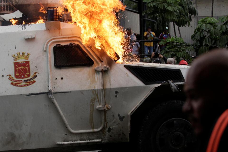  Demonstrators cheer as the armoured van is engulfed in flames