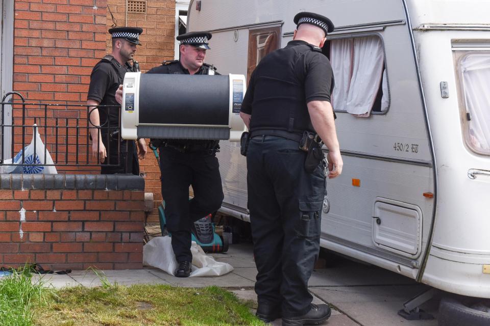  Police are seen carrying evidence from the scene in Liverpool on Monday