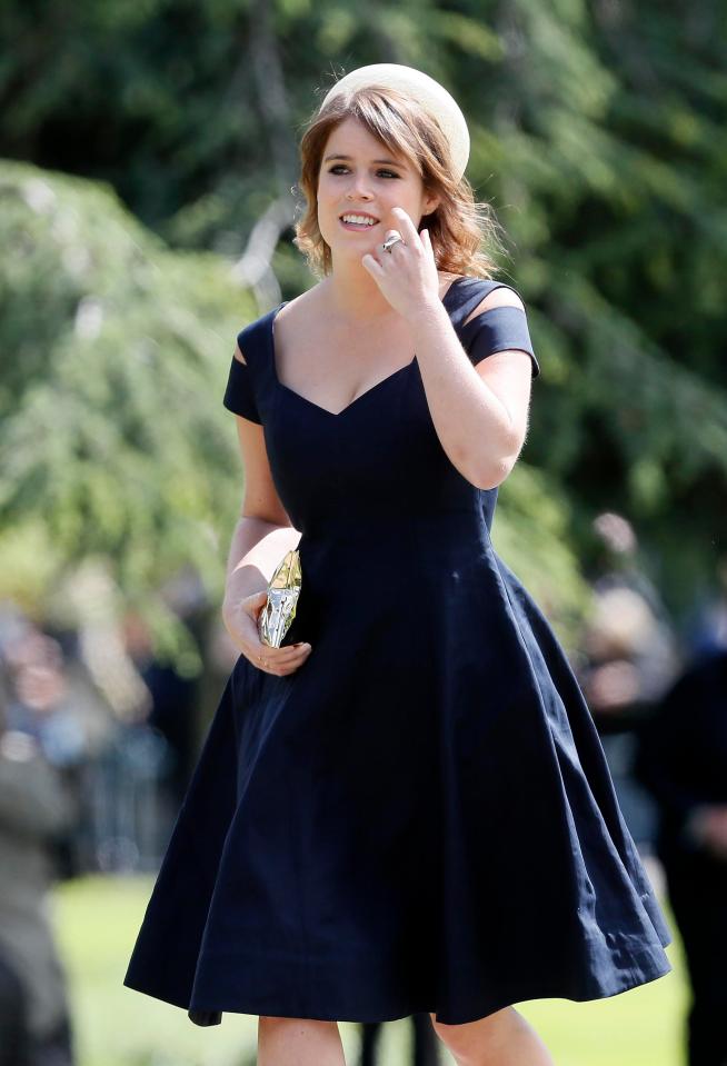  Princess Eugenie holds a gold clutch bag as she wears sweet navy blue dress