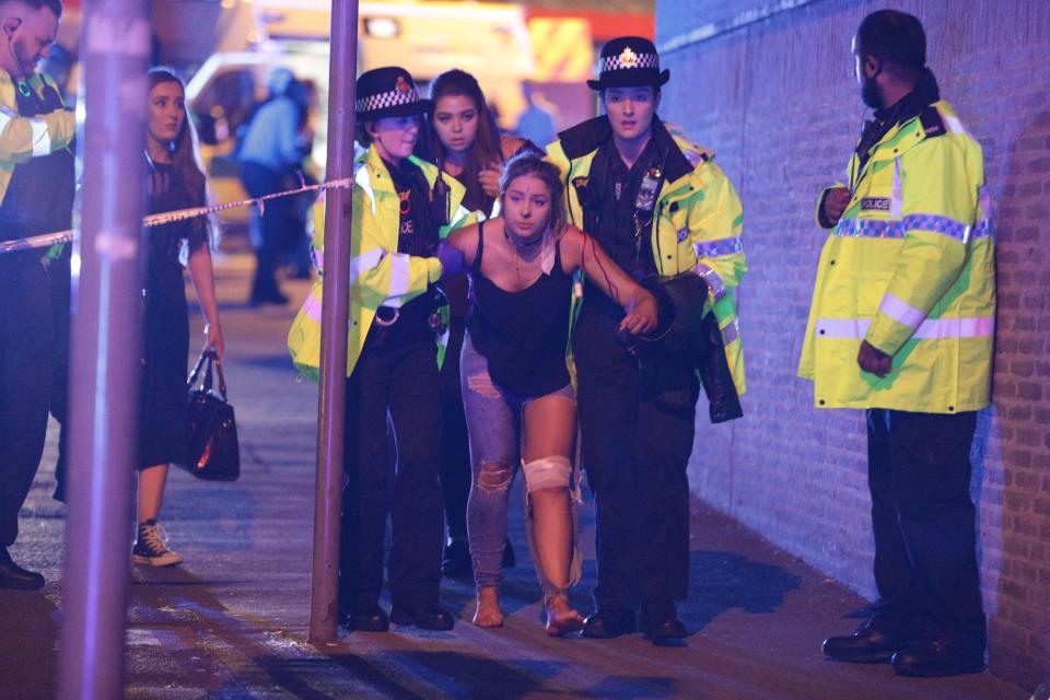  An injured woman is escorted from the arena by police after loud bangs were heard at the Ariana Grande gig