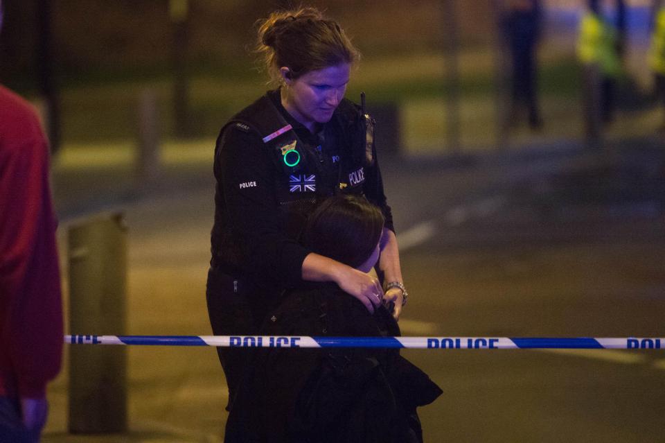  A police officer hugs a girl caught up in last night's horror