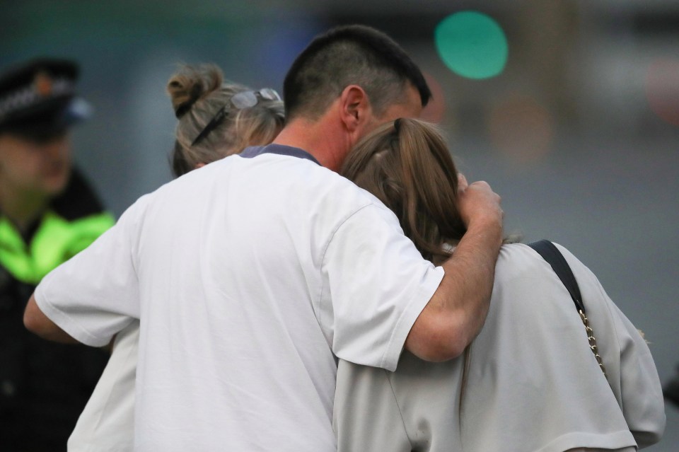 A man embraces a woman and a teenager as he collects them from the Park Inn Hotel where they were given refuge after last night's explosion