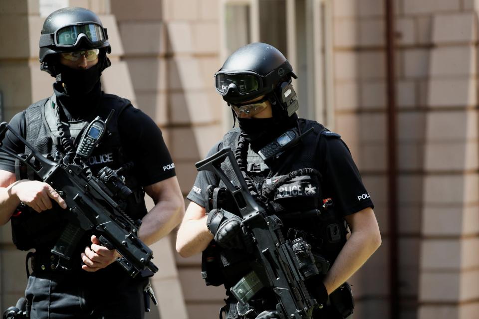  Armed police officers stand outside a residential property near to where a man was arrested in the Chorlton area of Manchester