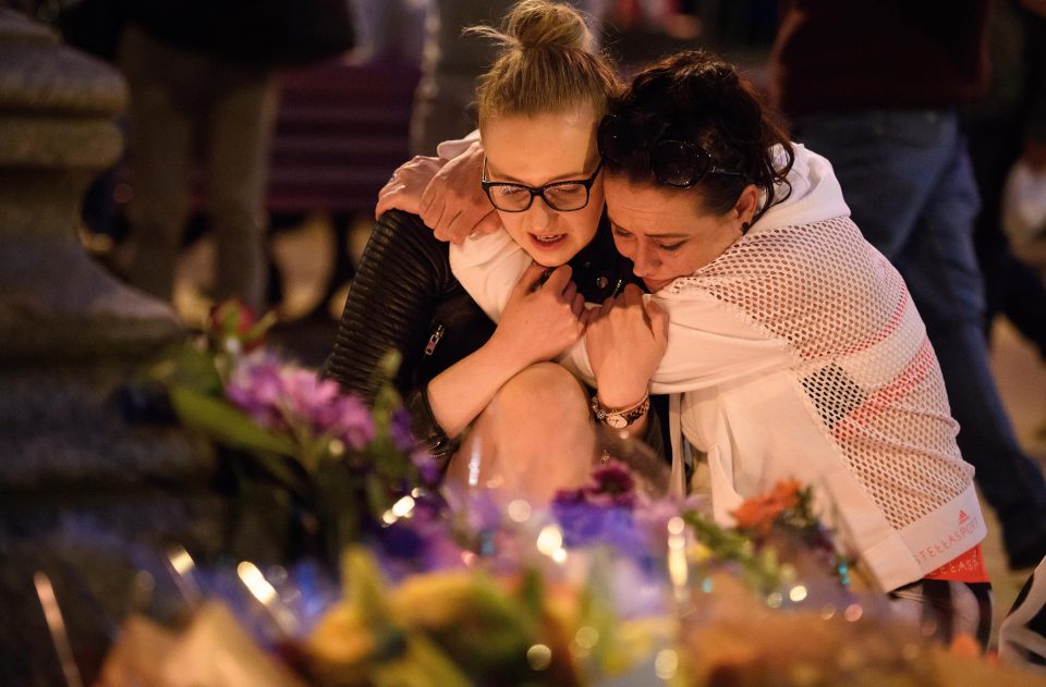  Mourners kneel before floral tributes outside Manchester Town Hall