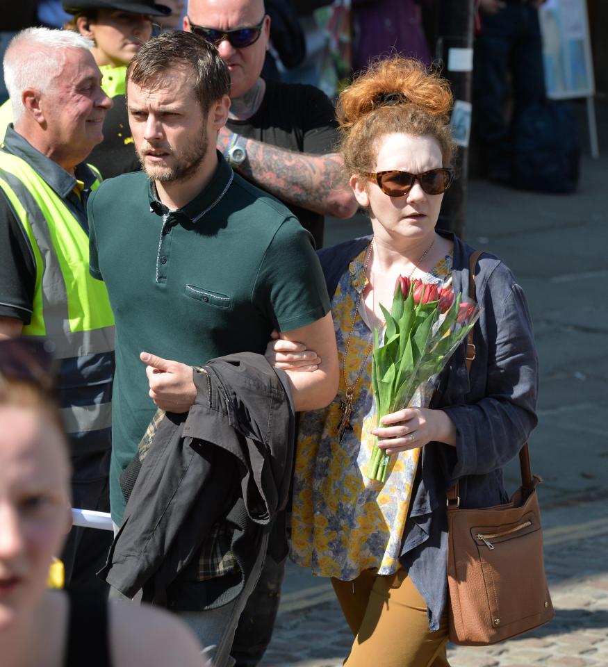  She clutched a bouquet of red flowers as she attended the one-minute silence at St Ann's Square