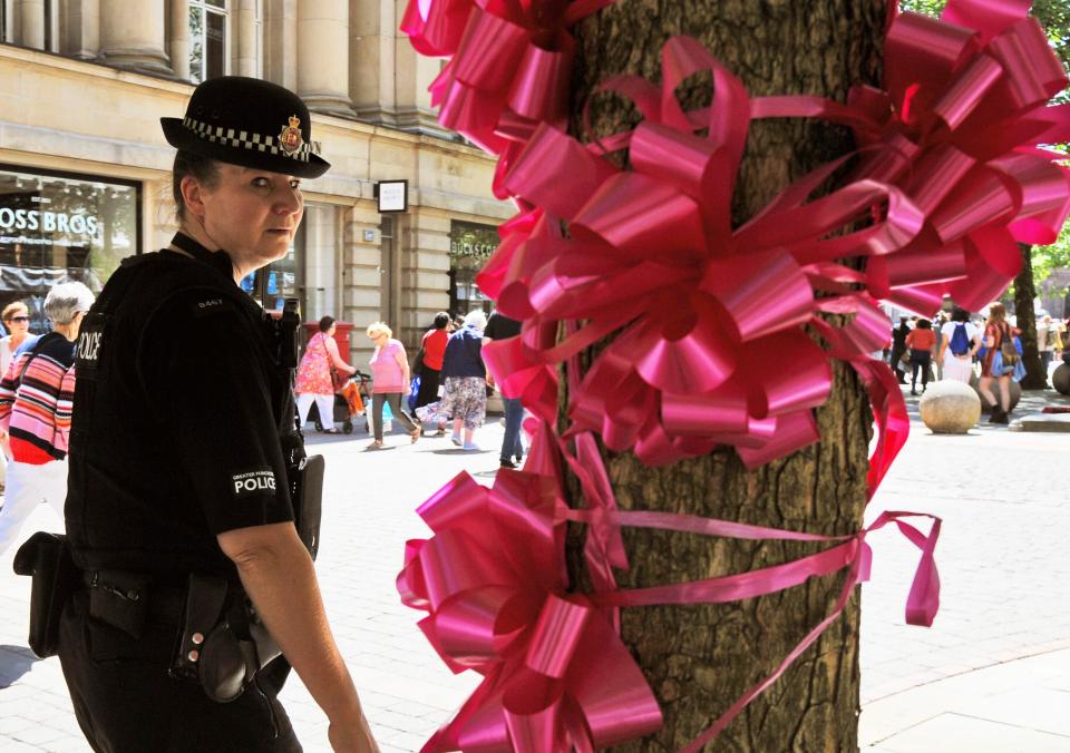  Police patrol past a pink ribbon tribute in central Manchester, England