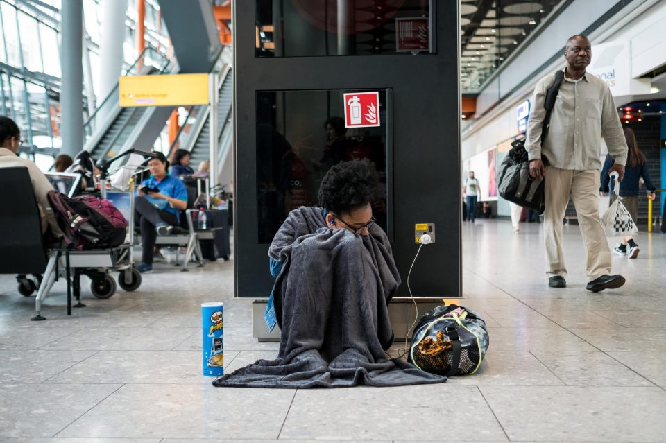  A woman sits charging her phone at the busy airport