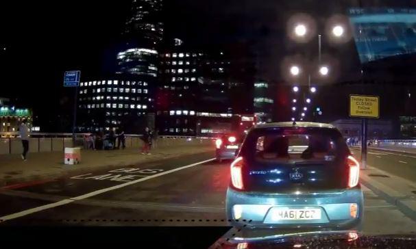  Stunned bystanders huddle together at the side of the road in dash-cam footage