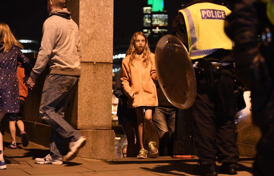  Another child looks terrified as she walks past armed cops near the scene of the attack in central London