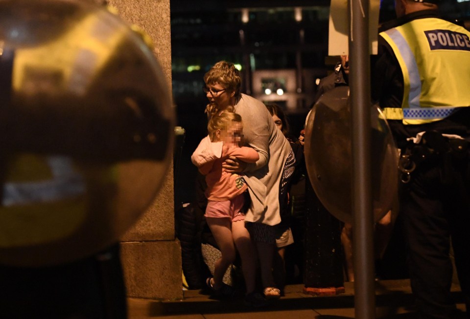 A scared little girl holds on to a woman with armed cops watching on in the UK capital