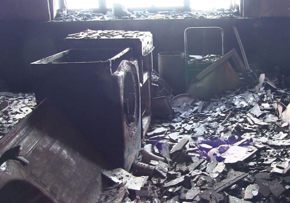 A hollowed out shell of a washing machine appears abanonded in the middle of the room – but the strength of the inferno destroyed the wall it was propped against