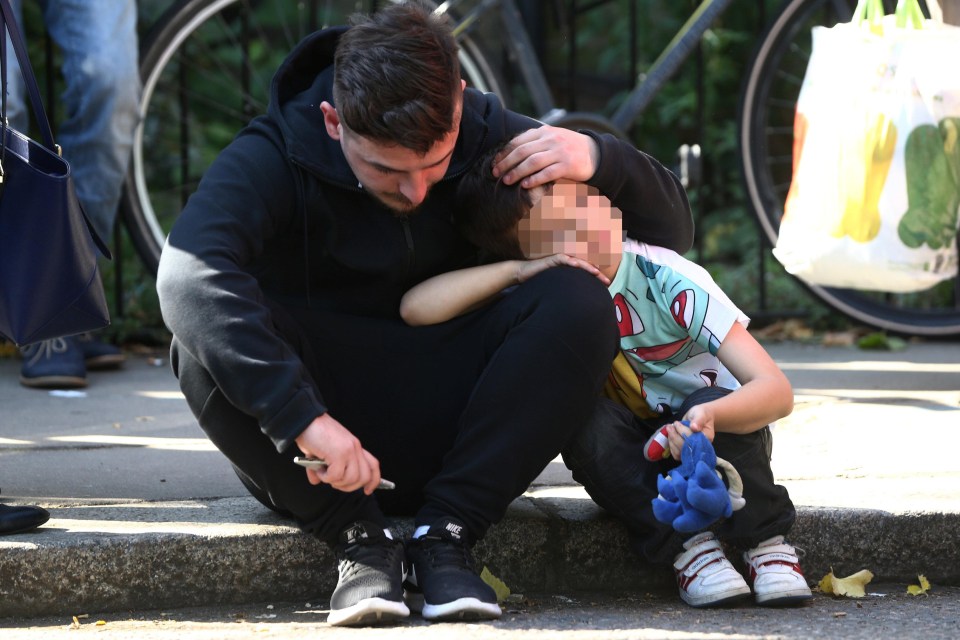 A man comforts a young boy at the scene as hundreds are evacuated amid fears for the building's stability