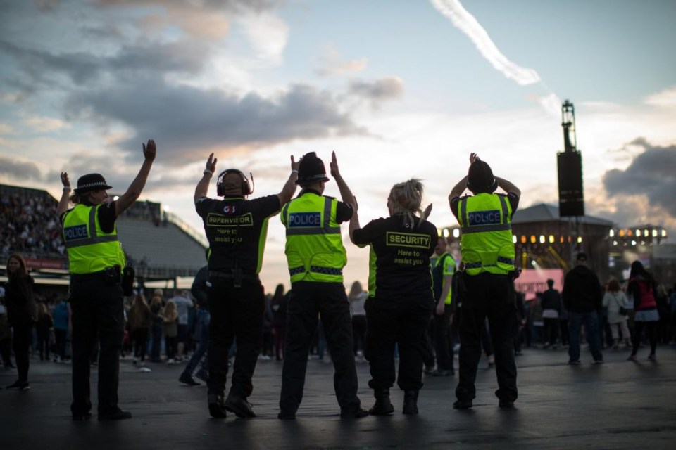 Police officers and security dance clap as they oversee then concert